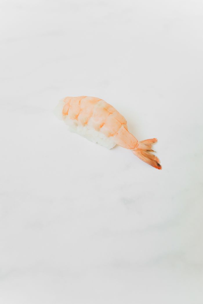 A minimalist photo of shrimp sushi on a white background, emphasizing simplicity.
